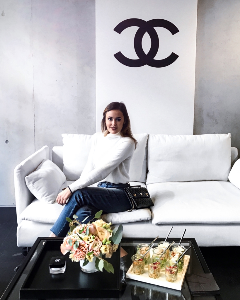 Blumen, Snacks, Sofa, weißer Pullover, Jeans, Tasche, Chanel-Logo