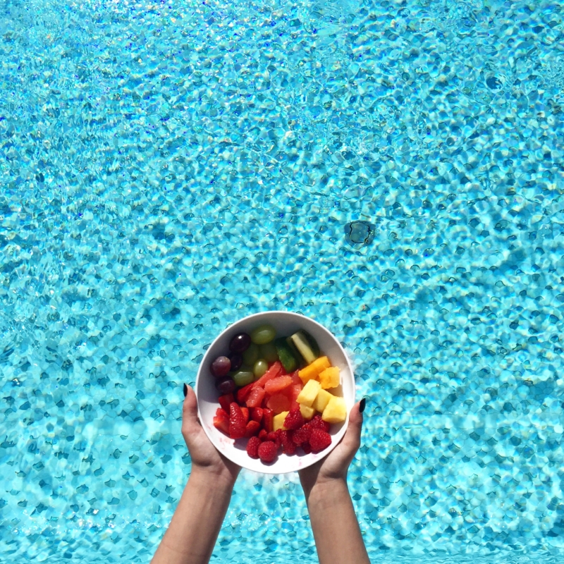bunter Obstsalat vor blauem Poolwasser